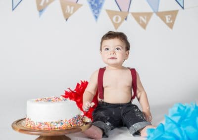 Baby boy in jeans in suspenders with smash cake in Photoplex Studios