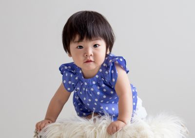 One Year Old Girl in Purple shirt Climbing up on box in Suwanee Studio