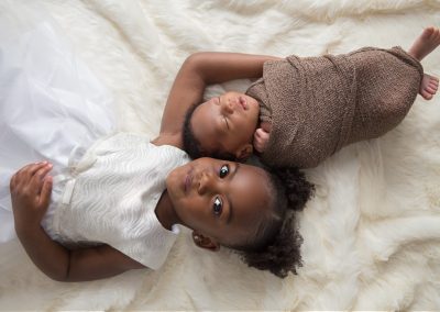 African american siblings on cream blanket during newborn photo shoot
