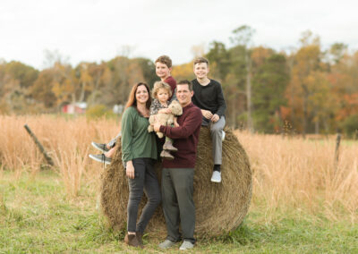 Family with two sons and young daughter in field in front of haystack in Lawrenceville, Georgia