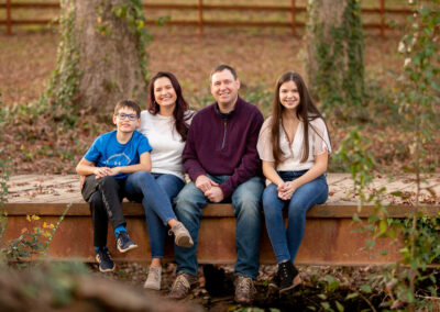 Family fo four with son and daughter sitting on bridge in Marietta park